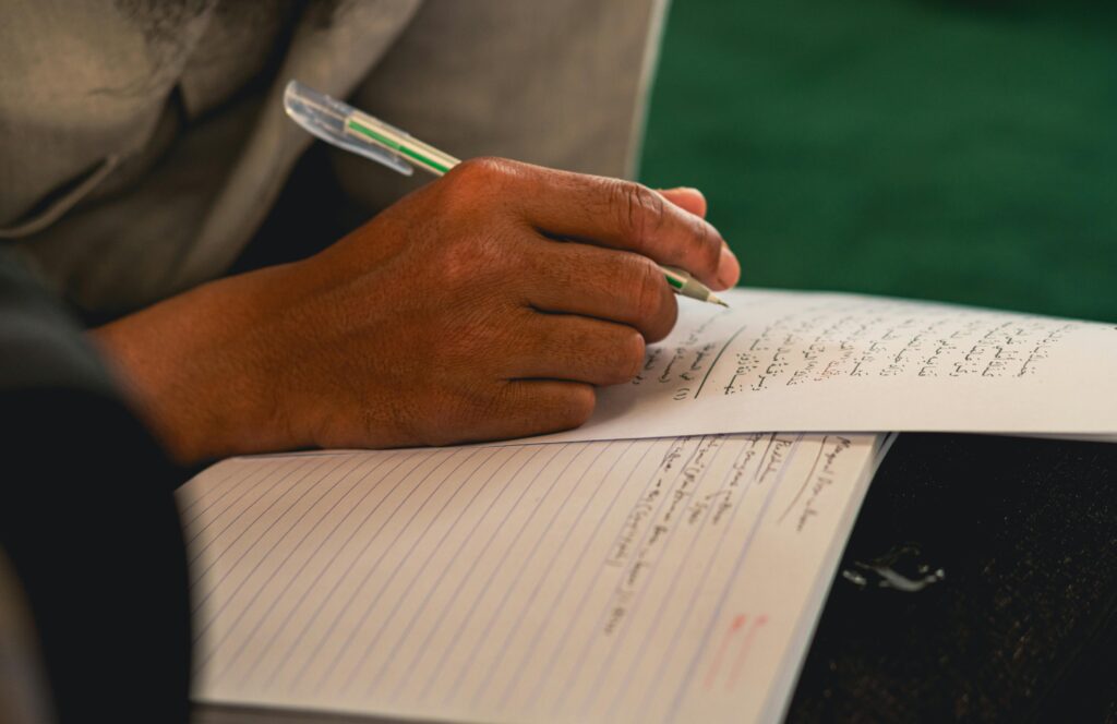 hand with pen writing on paper